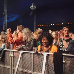 Menschen genießen ein soul festival, lachen und klatschen. Eine Frau in Orange strahlt in die Kamera.