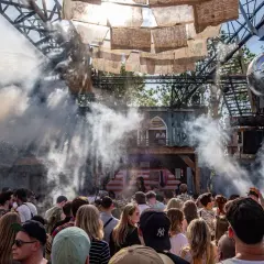 Menschenmenge bei einem Festival in den Woodlands Hildesheim, umgeben von Rauch und Dekorationen.