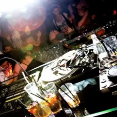 DJ-Pult mit Drinks und tanzenden Menschen im Hintergrund. Ein typischer Abend im **lifestyle club**.