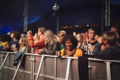 Menschen genießen ein soul festival, lachen und klatschen. Eine Frau in Orange strahlt in die Kamera.