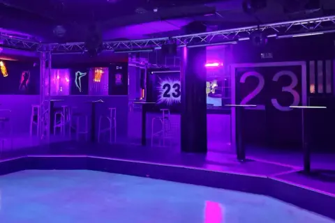 Der leere Dancefloor im Club 23 Rothenburg, beleuchtet in lila und blauem Licht. Hohe Tische und Barhocker stehen bereit.