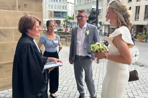 Hochzeitsmesse Heilbronn: Ein Paar feiert seine Hochzeit mit einem Blumenstrauß vor einer Kirche.