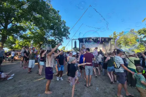Seifenblasen schweben über einer fröhlichen Menge beim weinturm open air. Kinder und Erwachsene genießen die sommerliche Atmosphäre vor der Bühne.