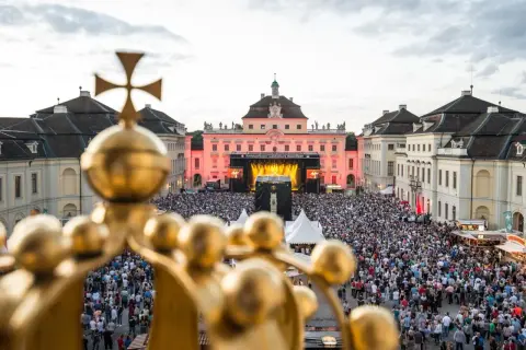 Goldener Blick auf ein riesiges Publikum bei **live musik ludwigsburg**. Die Barockfassade des Schlosses erstrahlt im Abendlicht.