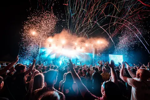Konfetti regnet auf ein jubelndes Publikum bei einem Festival. Die Bühne ist hell beleuchtet, die Stimmung ist ausgelassen: ab geht die Lutzi!