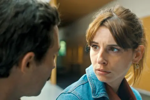Ein Mann und eine Frau im Gespräch, die Frau trägt eine Jeansjacke. Szenen aus ehrliche leute staffel 2.