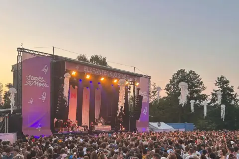 Große Menschenmenge feiert beim Stadt ohne Meer Festival. Die Elefantenklo Stage ist beleuchtet, Quallen-Deko schwebt in der Luft.