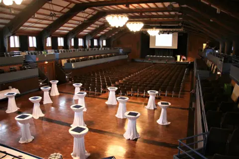 Innenansicht der Stadthalle Herrenberg mit vielen Sitzreihen, einer Bühne und Stehtischen, bereit für eine Veranstaltung.