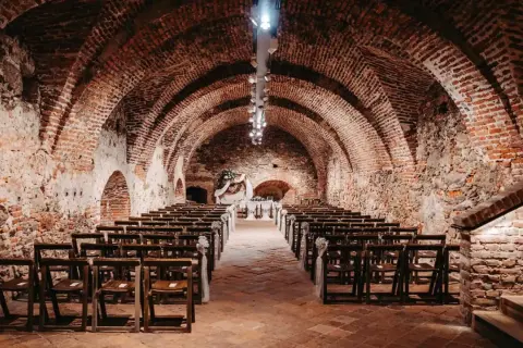 Historische Gewölbe des Kulturvereins Glems, bereit für eine Zeremonie mit Reihen von Holzstühlen und einem festlichen Altar.