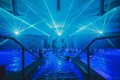 Blaue Laserstrahlen tanzen über einem Pool voller Menschen. Ein unvergessliches Erlebnis bei den Veranstaltungen in Bad Windsheim.