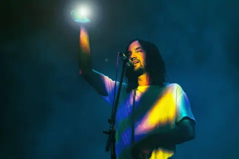 Kevin Parker von Tame Impala in Frankfurt, mit einem Lichtstrahl in der Hand.