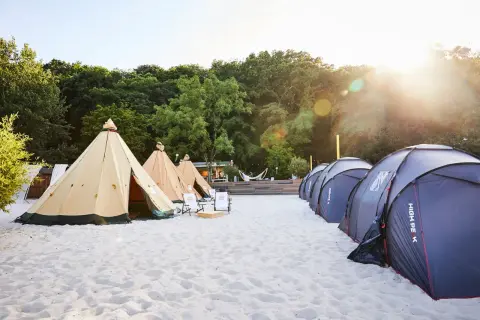 Zelte am Strand, bereit für den Summerjam Comfort Camp. Sonnenschein und entspannte Atmosphäre.