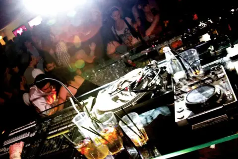 DJ-Pult mit Drinks und tanzenden Menschen im Hintergrund. Ein typischer Abend im **lifestyle club**.