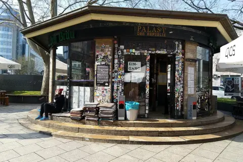 Der "Palast der Republik Stuttgart" ist ein Kiosk, der mit vielen Stickern beklebt ist. Eine Person sitzt davor.
