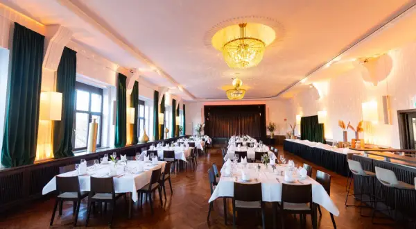 Festlich gedeckte Tische im Bootshaus Neckarsulm, bereit für Gäste. Kronleuchter und warme Beleuchtung schaffen eine elegante Atmosphäre.