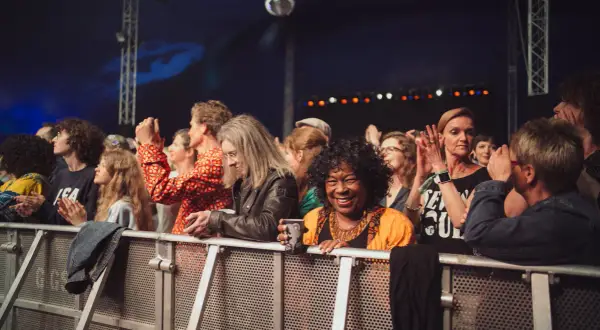 Menschen genießen ein soul festival, lachen und klatschen. Eine Frau in Orange strahlt in die Kamera.