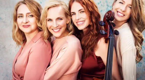 Vier lächelnde Frauen, eine davon hält ein Cello. Salut salon mitglieder, bereit für den Auftritt.