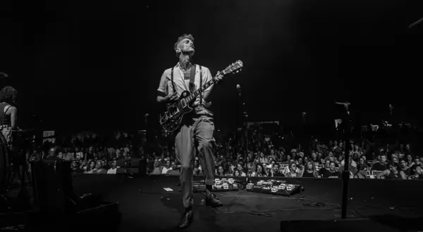 Asaf Avidan spielt in Berlin. Ein Mann mit Gitarre auf der Bühne, das Publikum im Hintergrund.