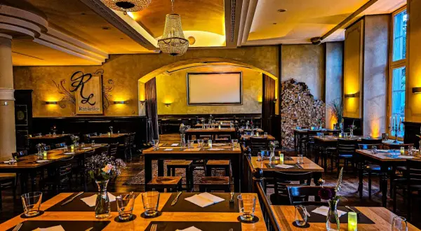 Gemütlicher Ratskeller Biergarten Ludwigsburg mit gedeckten Tischen, Kronleuchtern und Kaminholz.