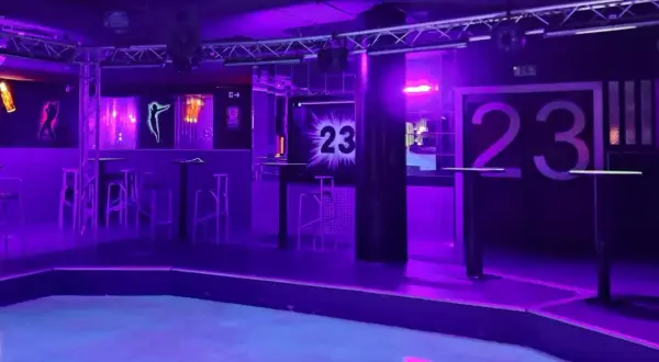 Der leere Dancefloor im Club 23 Rothenburg, beleuchtet in lila und blauem Licht. Hohe Tische und Barhocker stehen bereit.