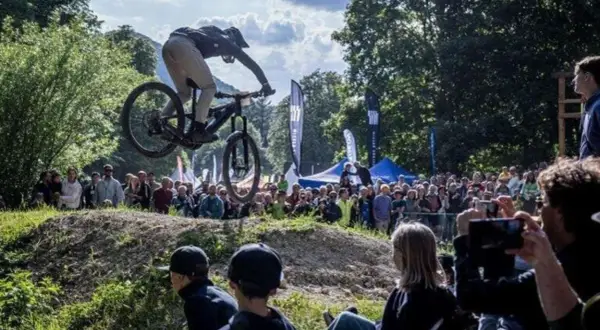 Mountainbiker springt bei einer Veranstaltung in Heubach heute über eine Schanze, während eine Menge zuschaut.