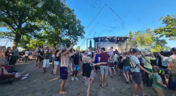 Seifenblasen schweben über einer fröhlichen Menge beim weinturm open air. Kinder und Erwachsene genießen die sommerliche Atmosphäre vor der Bühne.