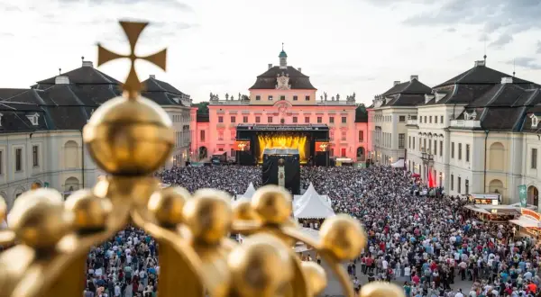 Goldener Blick auf ein riesiges Publikum bei **live musik ludwigsburg**. Die Barockfassade des Schlosses erstrahlt im Abendlicht.