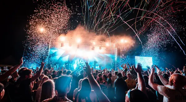 Konfetti regnet auf ein jubelndes Publikum bei einem Festival. Die Bühne ist hell beleuchtet, die Stimmung ist ausgelassen: ab geht die Lutzi!