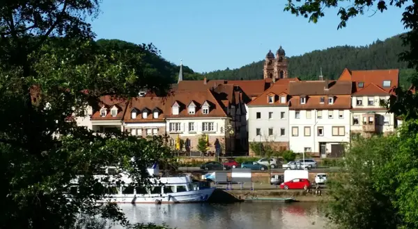 Idyllische Kulisse am Flussufer mit Fachwerkhäusern und Kirchturm. Vielleicht gibt es heute Veranstaltungen in Mosbach?