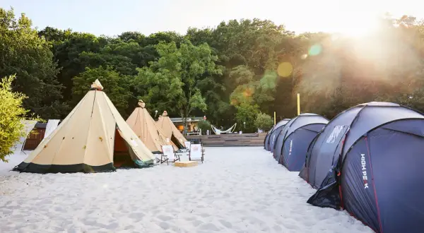 Zelte am Strand, bereit für den Summerjam Comfort Camp. Sonnenschein und entspannte Atmosphäre.