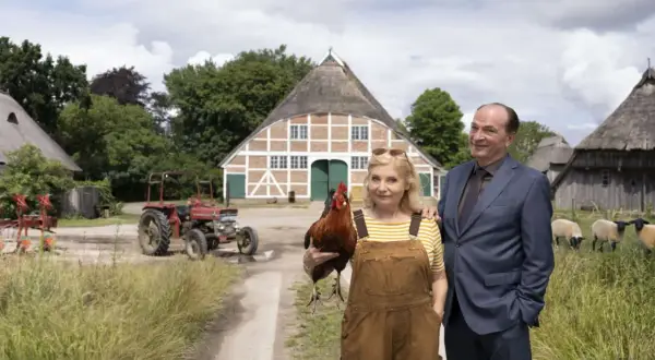 Ein Mann im Anzug und eine Frau mit Latzhose und Huhn stehen vor einem Bauernhaus. Im **weiten Land** grasen Schafe, ein Traktor steht bereit.