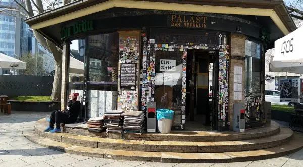 Der "Palast der Republik Stuttgart" ist ein Kiosk, der mit vielen Stickern beklebt ist. Eine Person sitzt davor.