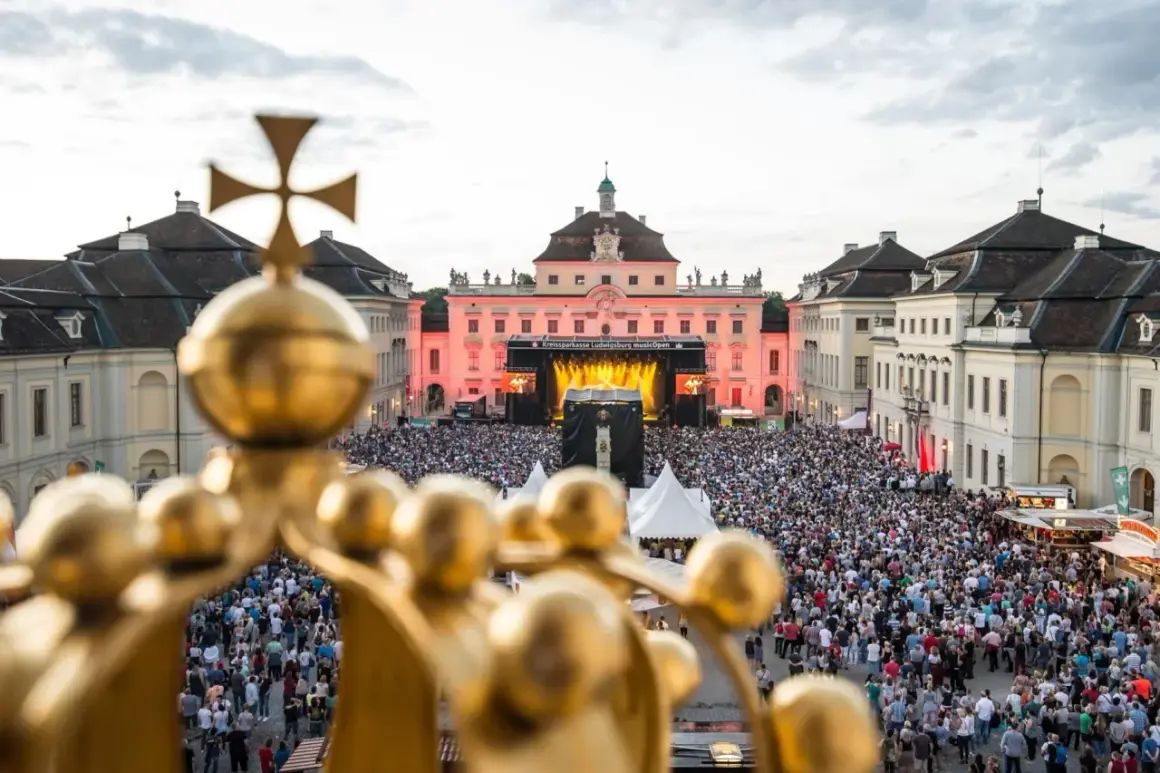 Goldener Blick auf ein riesiges Publikum bei **live musik ludwigsburg**. Die Barockfassade des Schlosses erstrahlt im Abendlicht.