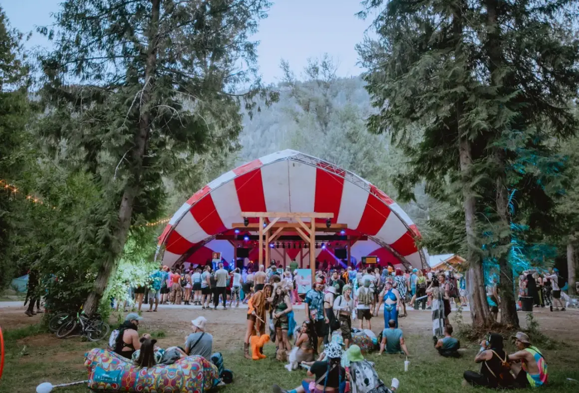 Bunte Menge feiert auf dem Shambhala Festival unter einem rot-weißen Zeltdach.