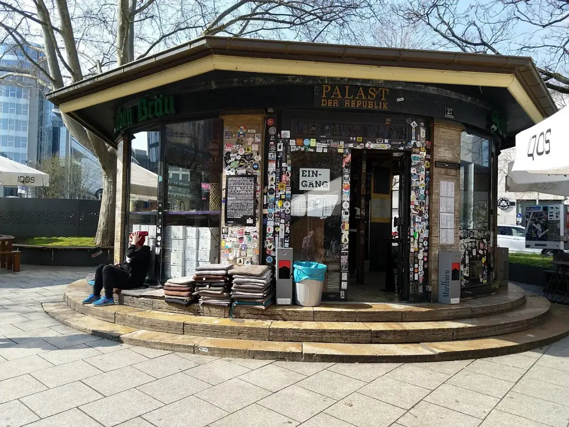 Der "Palast der Republik Stuttgart" ist ein Kiosk, der mit vielen Stickern beklebt ist. Eine Person sitzt davor.