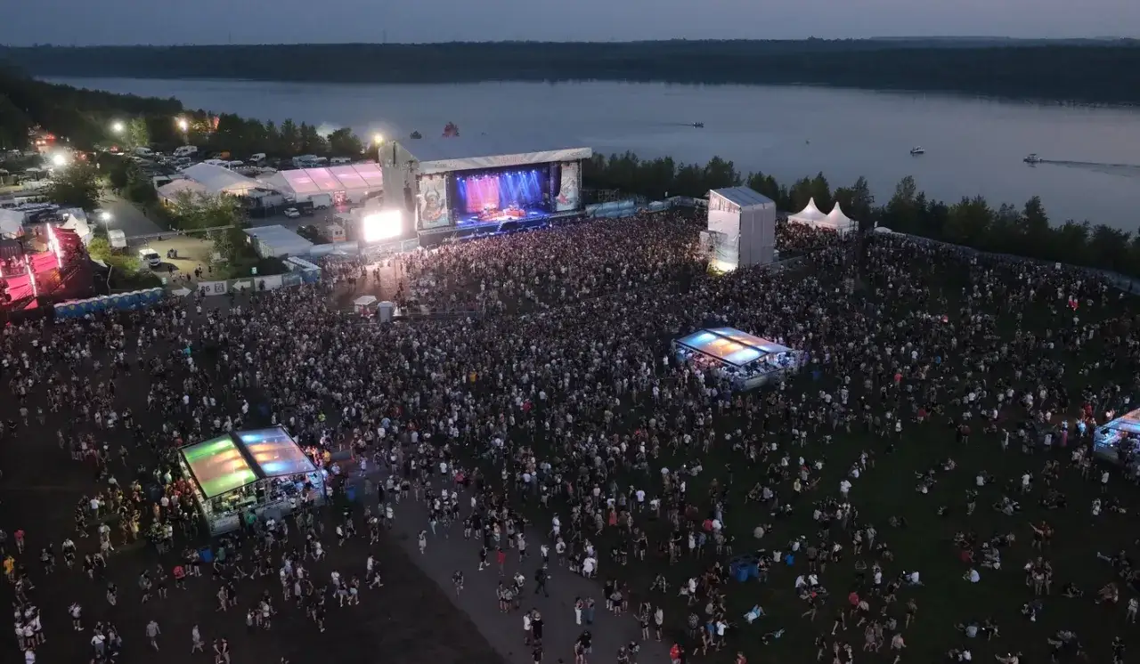 Tausende feiern beim Highfield Festival Leipzig am Stausee. Eine riesige B&uuml;hne mit Lichtern und eine Menschenmenge, die tanzt.