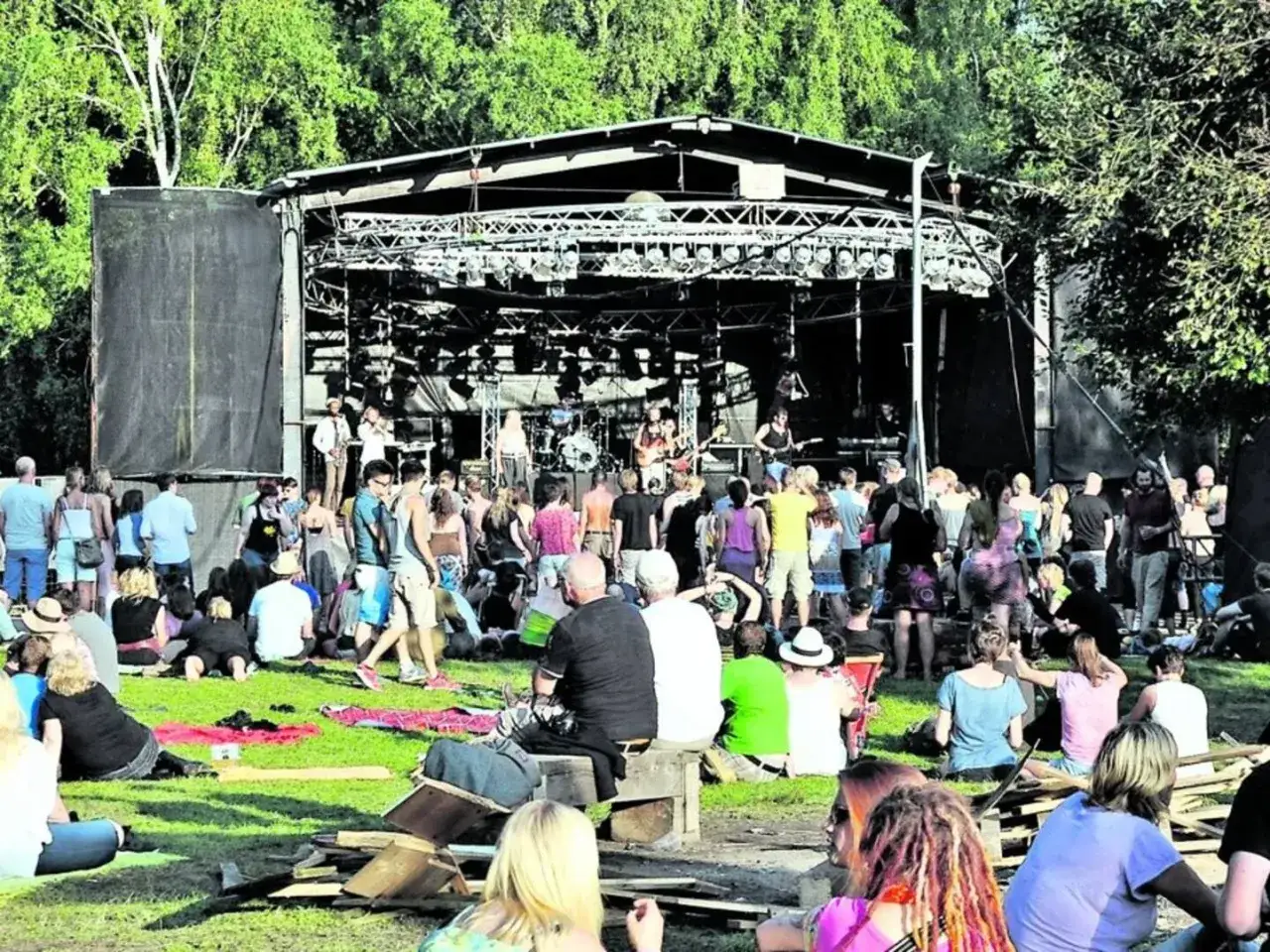 Menschen genie&szlig;en ein Konzert beim zytanien festival. Eine Band spielt auf der B&uuml;hne, w&auml;hrend das Publikum auf Decken und im Gras sitzt.