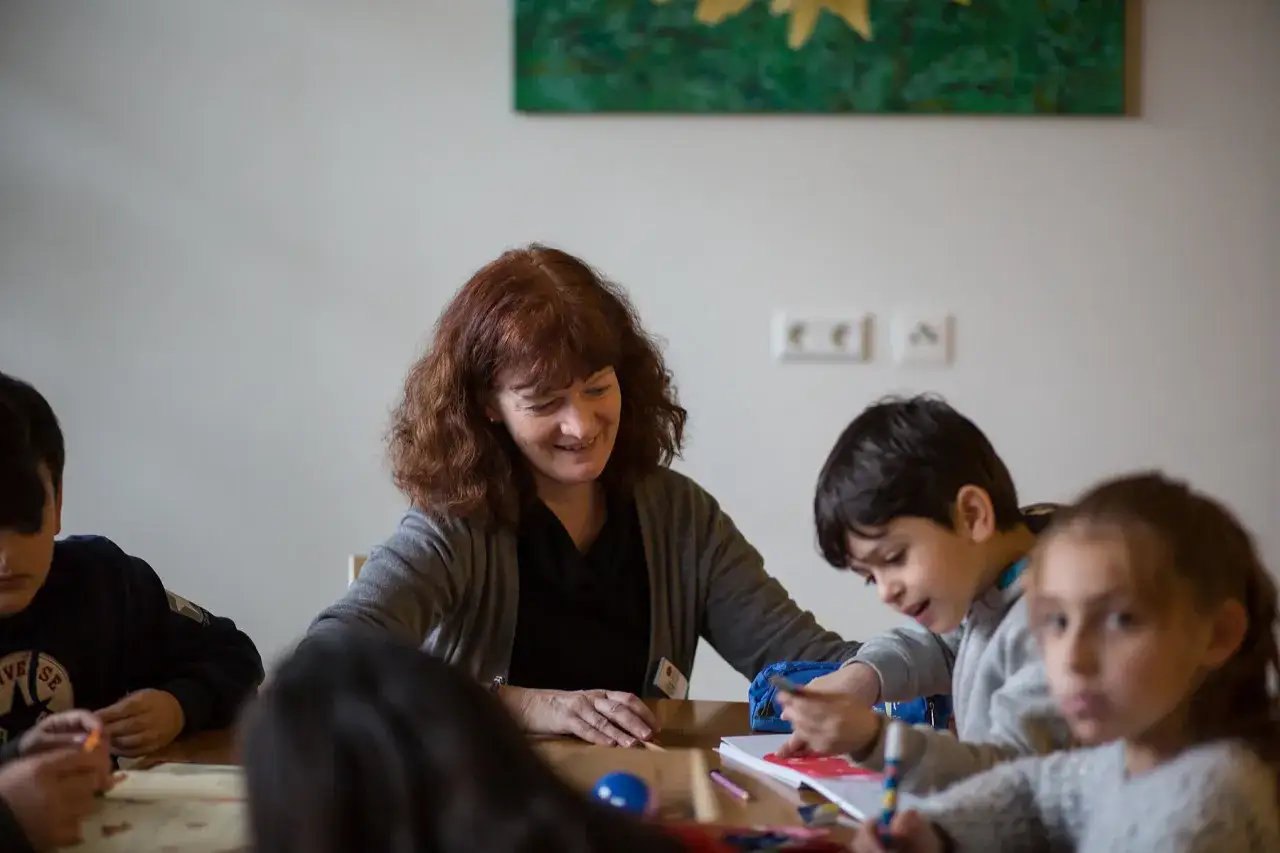 Eine Frau hilft Kindern beim Malen im Mehrgenerationenhaus Heilbronn.